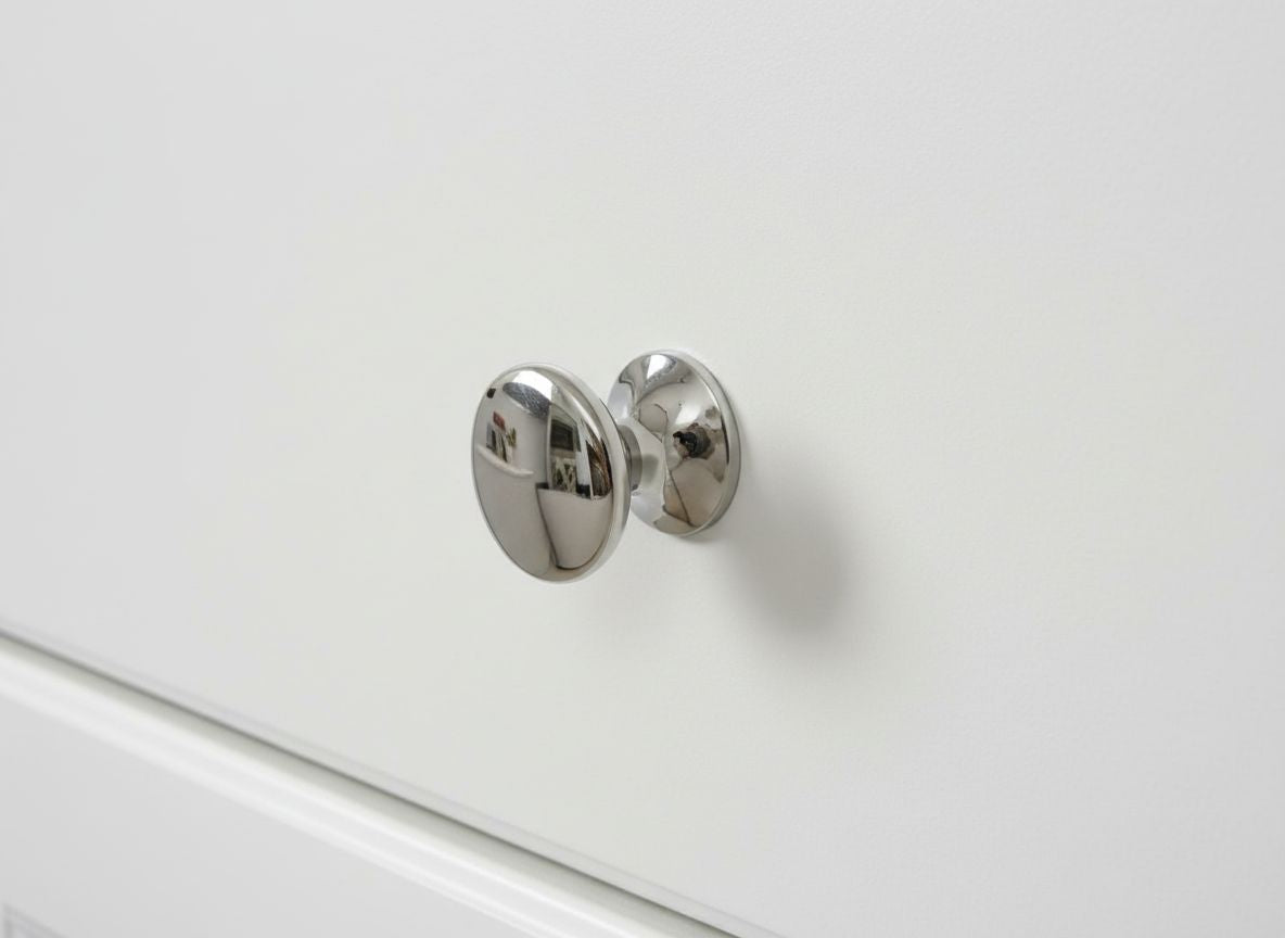 Chrome cabinet knob on a white drawer