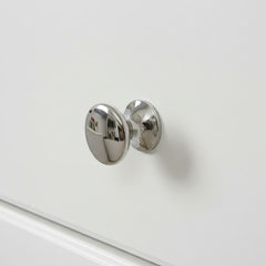 Chrome cabinet knob on a white drawer