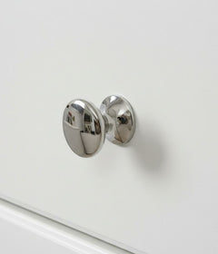 Chrome cabinet knob on a white drawer